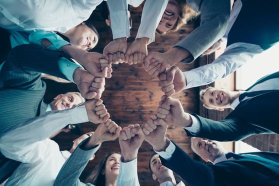 Group hold hands and fists together to celebrate project prize nomination.