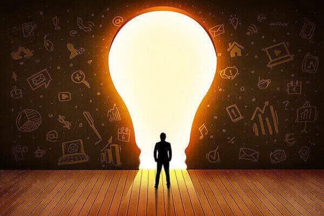 Person standing in front of a giant lightbulb.