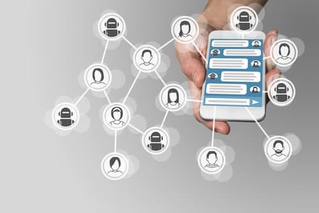 Person holding a cell phone, with icons of people floating around it.