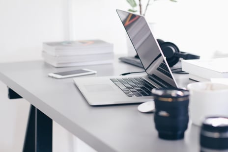 Sleek office setup with laptop and camera lens showing how to use video marketing for content creation.