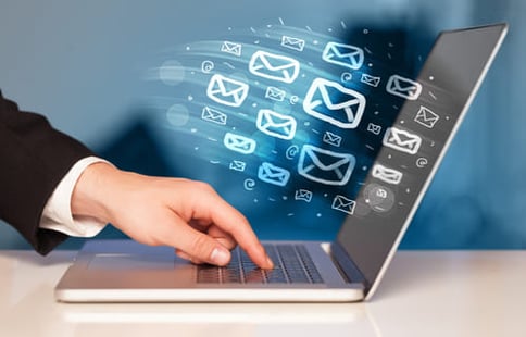 Emails flying from a laptop screen symbolizing the question: is email marketing still relevant in digital business.