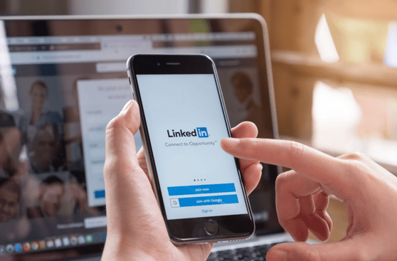 Person accessing LinkedIn account types via smartphone with LinkedIn login screen displayed.